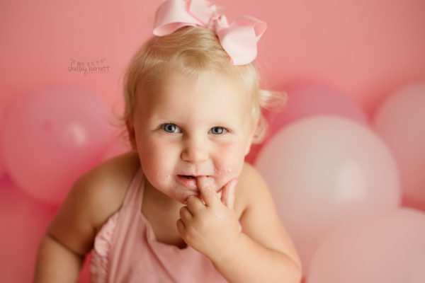 Two year old toddler girl take portraits and smashed cake at Pensacola Photography studio.