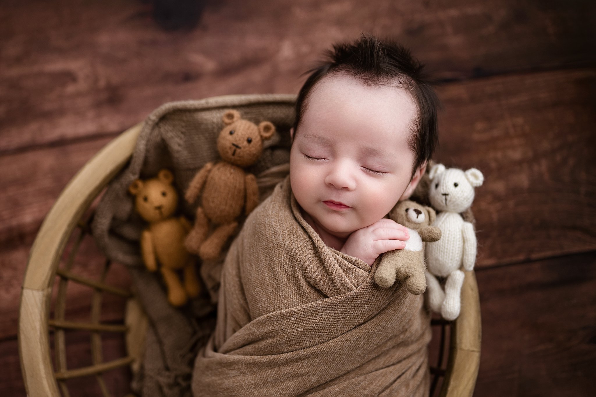 Wrapped newborn baby sleeping in a prop with teddy bears during a studio session with a Birmingham newborn photographer in Springville, Alabama.