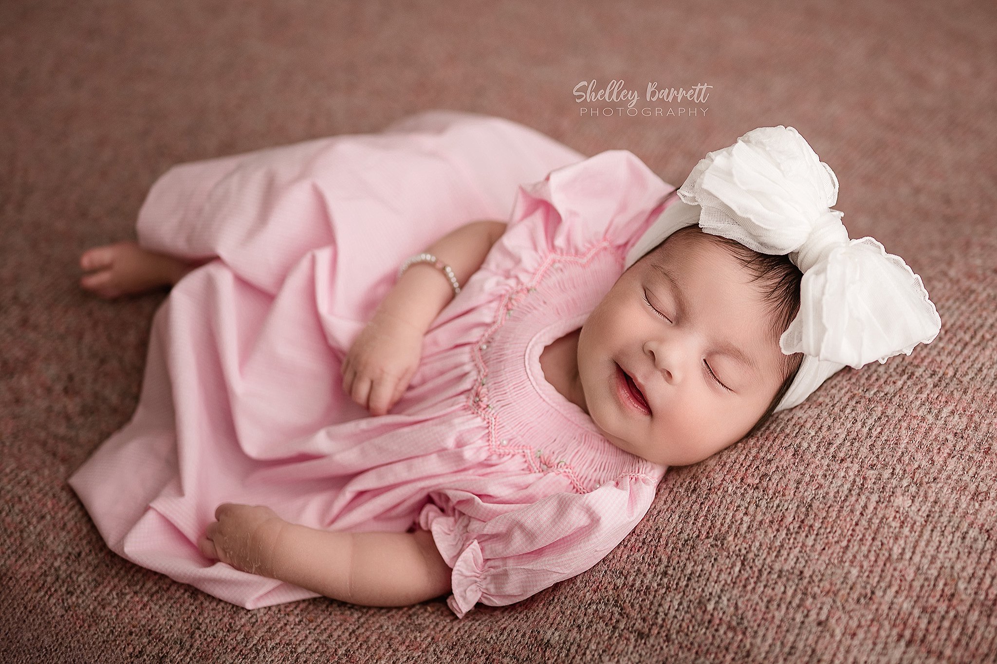 Sleeping newborn photographed smiling by a Springville newborn photographer in Trussville, Alabama