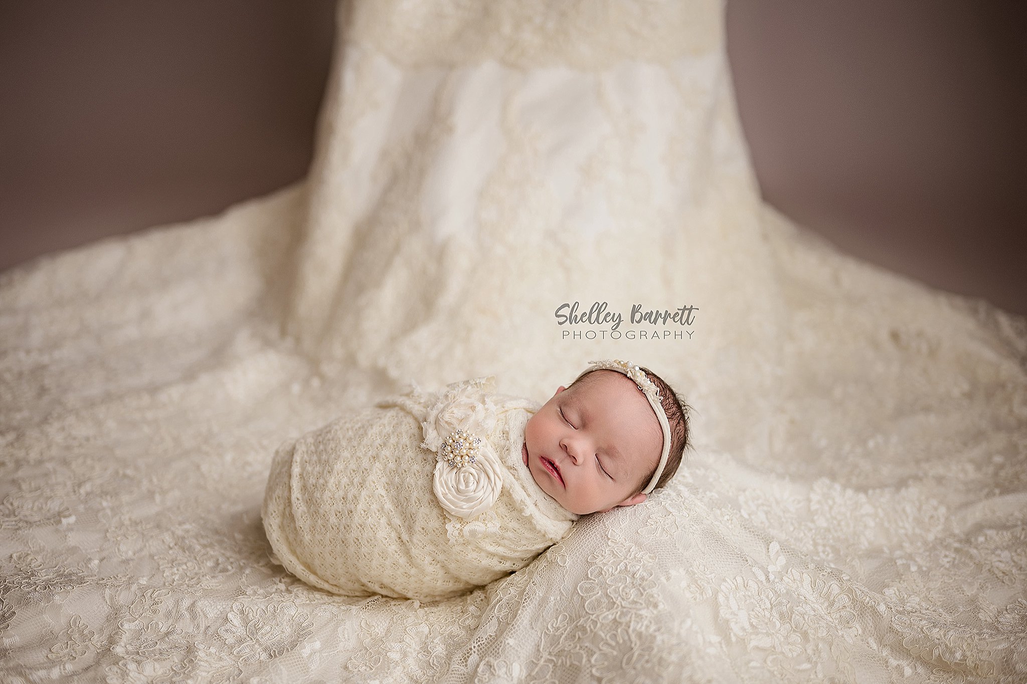 Newborn baby sleeping during a Birmingham newborn photography session on mom's wedding dress