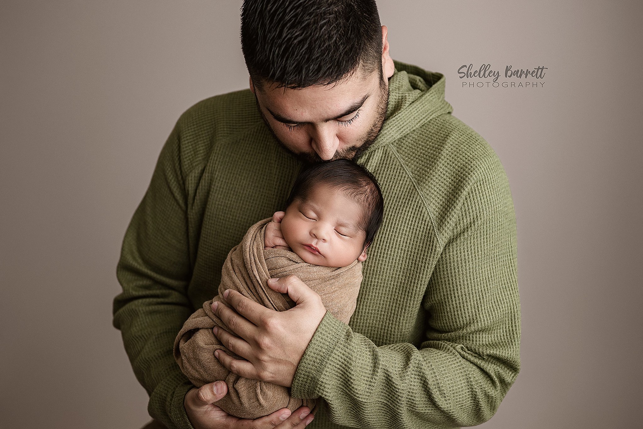 Father kissing newborn baby's forehead during a newborn photography session