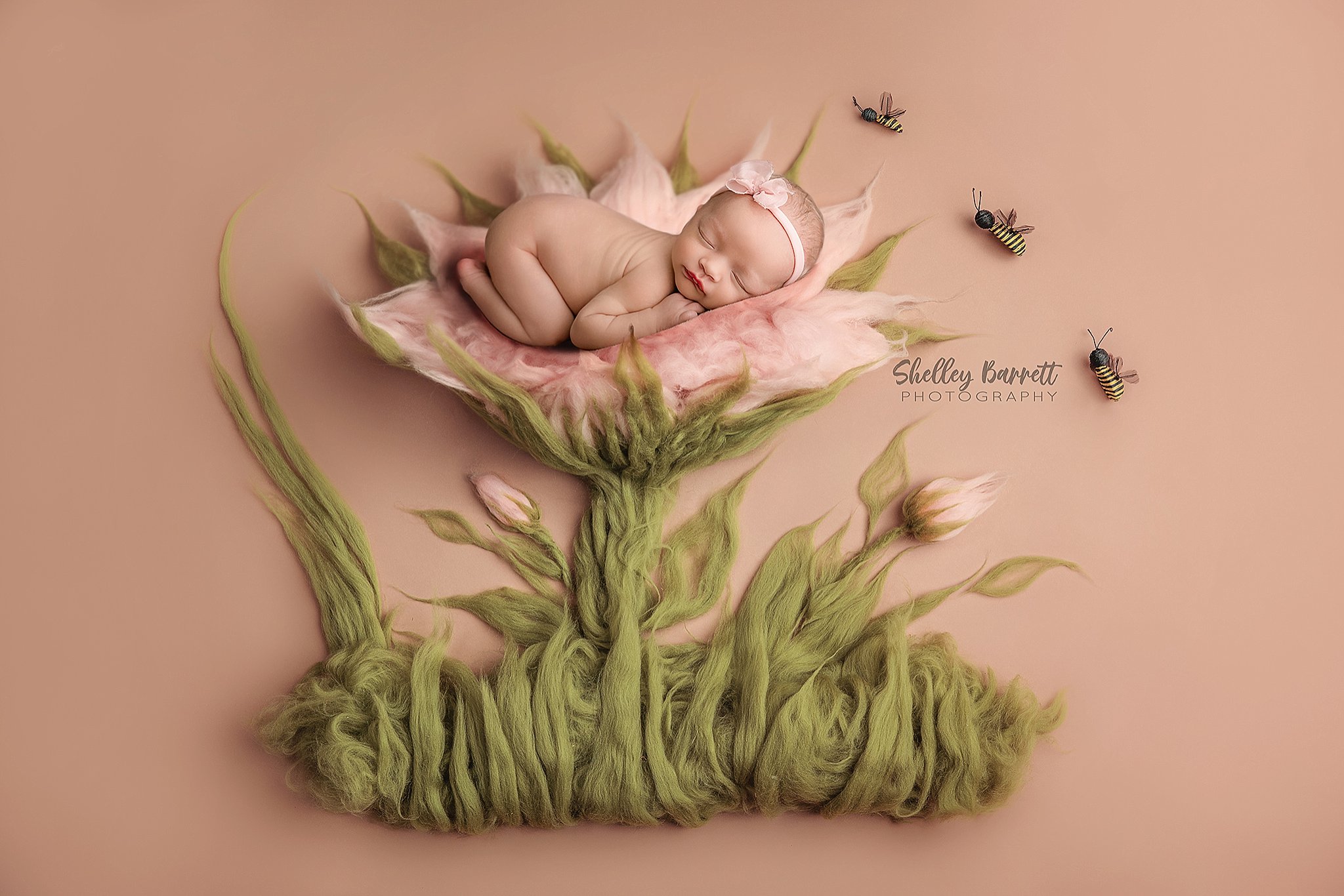 Newborn baby sleeping peacefully in a Trussville newborn photography studio composite of blooming flower with bumblebees