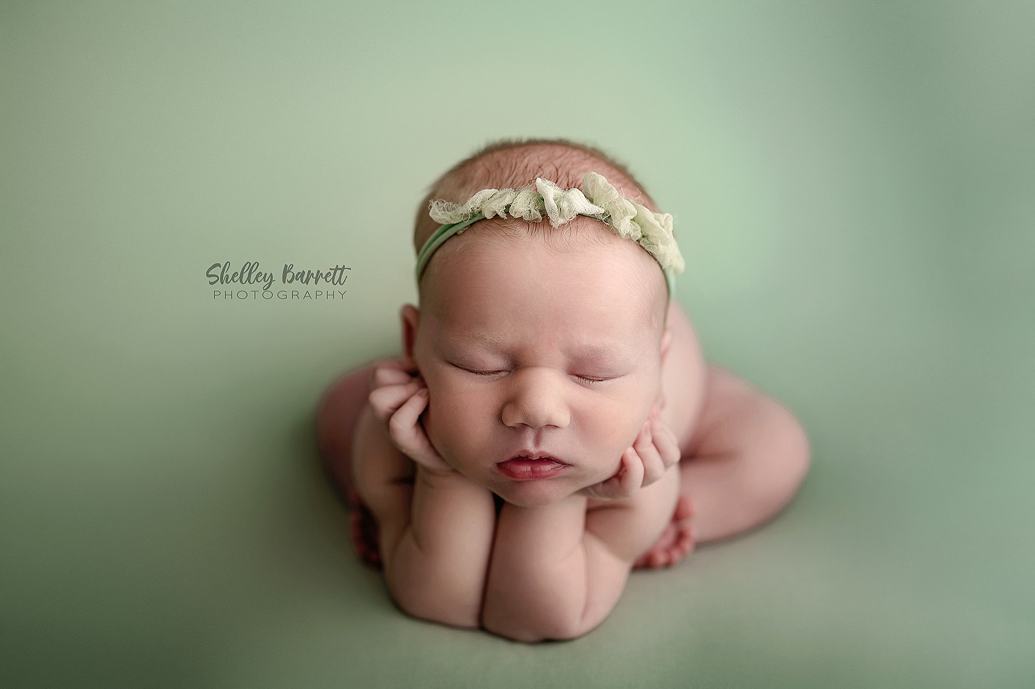 Beautiful newborn baby girl peacefully posed on a mint green blanket at a Springville, Alabama newborn photography studio.